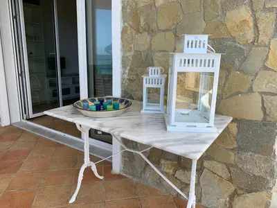 a white table with a bowl on it next to a stone wall at Sfondo Blu Villa sul mare in Trabia