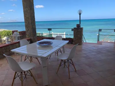 a white table and chairs on a patio with the ocean at Sfondo Blu Villa sul mare in Trabia