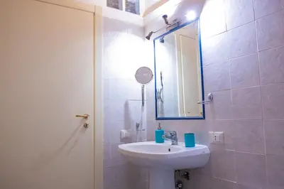 a white bathroom with a sink and a mirror at Centro Casa Monteleone in Palermo