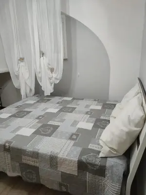 a bedroom with a bed with a blanket and curtains at Alla Casetta in Palermo