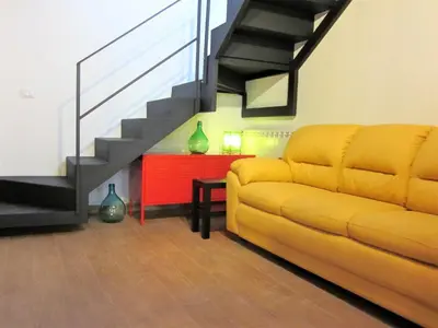 a living room with a yellow couch and a staircase at icalderai in Palermo