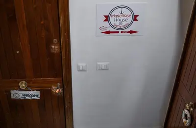 a door with a sign on the side of a house at MarieRose House Sferracavallo in Sferracavallo