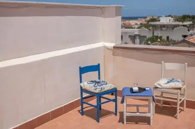 two chairs sitting on a balcony with a glass of wine at MarieRose House Sferracavallo in Sferracavallo