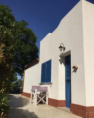 a white building with a table and a blue door at Petruso Resort e SPA in Balestrate