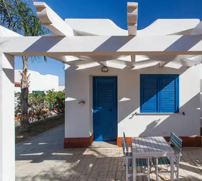 a white house with a blue door and a table at Petruso Resort e SPA in Balestrate
