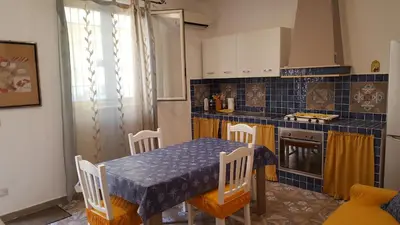 a kitchen with a table and a blue tiled wall at Casa Baarìa in Bagheria