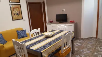 a dining room with a table and a yellow couch at Casa Baarìa in Bagheria