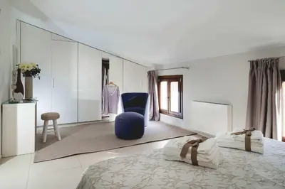 a bedroom with a bed and a blue chair at Nettuno in Cefalù