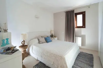 a white bedroom with a bed and a window at Nettuno in Cefalù