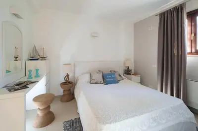 a white bedroom with a white bed and a desk at Nettuno in Cefalù