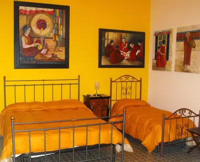 two beds in a room with yellow walls at B&B Casa Degli Artisti in Palermo