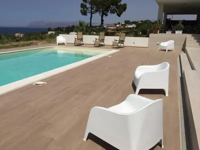 a swimming pool with white chairs next to a swimming pool at Villa Flo in Castellammare del Golfo