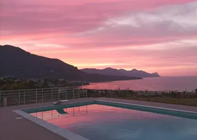a swimming pool with a view of the ocean at sunset at Villa Flo in Castellammare del Golfo