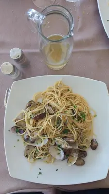 a plate of pasta with oysters and a glass of water at Porta Nuove Vacanze in Palermo