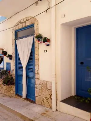 a blue door with a curtain on the side of a building at Casa vacanze Al porticciolo romantico in Trappeto