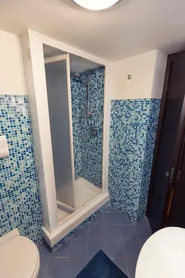 a bathroom with a toilet and a shower with blue tiles at Vista Cattedrale in Palermo