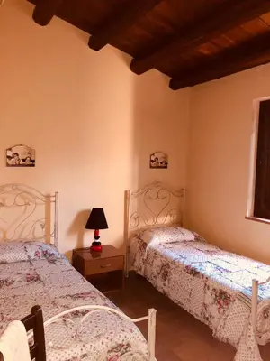 a bedroom with two beds and a lamp on a table at Agriturismo Ilardo in Collesano