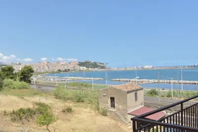 a building on a hill next to a body of water at Dependance La Mouette in Termini Imerese