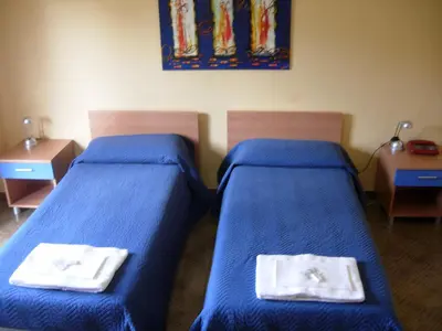 two beds in a room with blue sheets and towels at Dependance La Mouette in Termini Imerese
