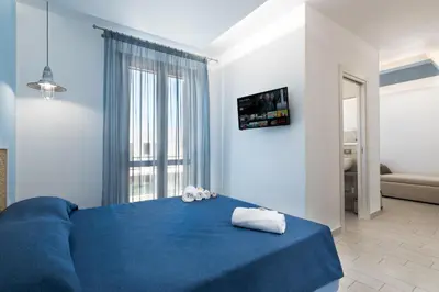 a blue bed in a room with a large window at B&B Reset confort & relax in San Vito lo Capo
