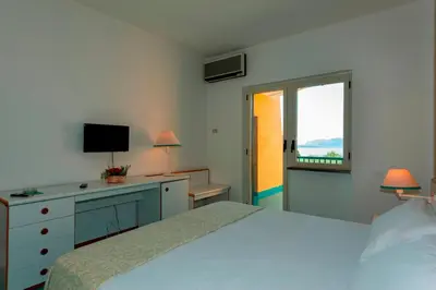 a bedroom with a bed and a television and a window at Hotel Torre Normanna in Altavilla Milicia