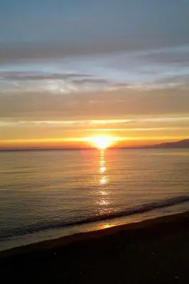 a sunset on the beach with the sun setting over the ocean at Sea Pearl in Casteldaccia
