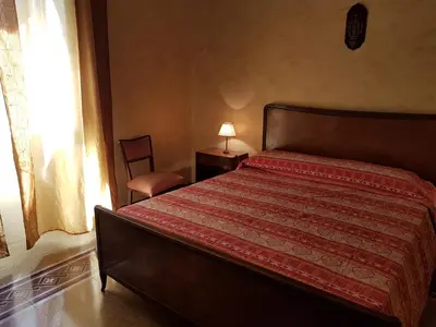 a bedroom with a bed and a chair and a window at B&B SAMMARTINO in Palermo