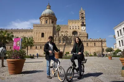 a man and woman riding bikes in front of a building at Ai Vicerè in Palermo