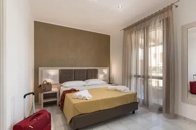 a hotel room with a bed and a red suitcase at La Dimora del Pescatore in San Vito lo Capo