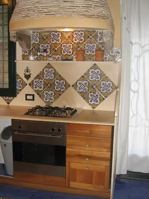 a kitchen counter with a stove and tiles on the wall at the ancient sicilian house near zingaro reserve Scopello in Scopello