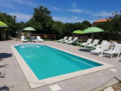 a swimming pool with chairs and umbrellas at House Cefalù 1915 in Lascari