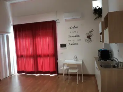 a kitchen with a red curtain and a table with chairs at Fuga Romantica vicino al Mare - Rental BeB in Balestrate