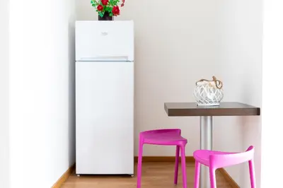 a white refrigerator next to a table with pink stools at Fuga Romantica vicino al Mare - Rental BeB in Balestrate