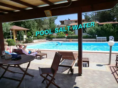 a group of people sitting around a table by a swimming pool at VILLASEASICILY , POOL SALT WATER and NATURAL CHLORINE IN BALESTRATE - PALERMO in Balestrate