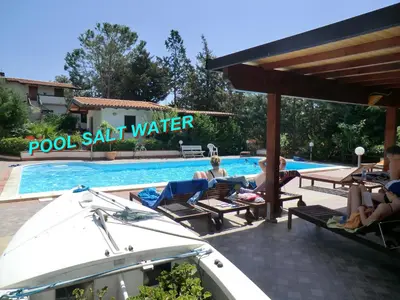 a group of people sitting in chairs by a swimming pool at VILLASEASICILY , POOL SALT WATER and NATURAL CHLORINE IN BALESTRATE - PALERMO in Balestrate