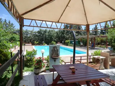a picnic table under an umbrella next to a swimming pool at VILLASEASICILY , POOL SALT WATER and NATURAL CHLORINE IN BALESTRATE - PALERMO in Balestrate