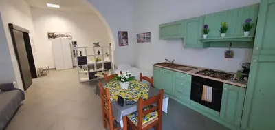 a kitchen with green cabinets and a table with chairs at Loft in Balestrate vicino al Mare - Rental BeB in Balestrate