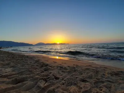 a beach with the sun setting in the ocean at Loft in Balestrate vicino al Mare - Rental BeB in Balestrate