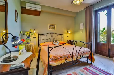 a bedroom with a bed and a table with a lamp at Al Lago Verde in Alia