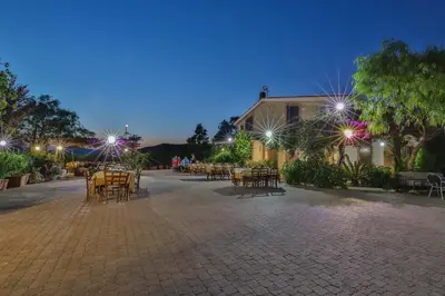a patio with tables and chairs at night at Al Lago Verde in Alia
