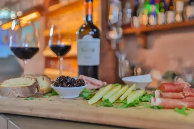 a table with a plate of food and a bottle of wine at Al Lago Verde in Alia