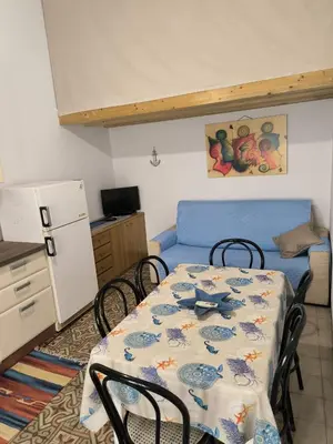 a kitchen with a table with chairs and a blue couch at Casa Trinita in Castellammare del Golfo