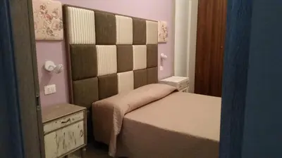 a small bedroom with a bed with a large headboard at Casa Marta in Palermo