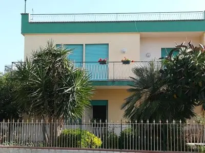a building with a balcony with palm trees in front of it at Le Terrazze in Carini