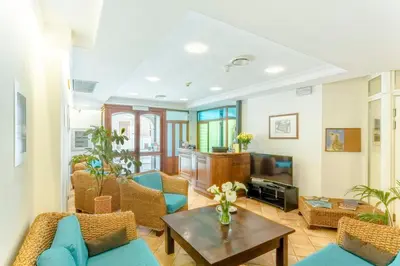 a living room with blue chairs and a table at Hotel Trinacria in San Vito lo Capo
