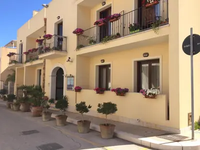 a building with potted plants on the side of it at Hotel Trinacria in San Vito lo Capo