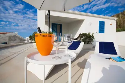 a table with wine glasses and an umbrella on a balcony at Marina Beach Resort by Le Dhome Sicily in Balestrate