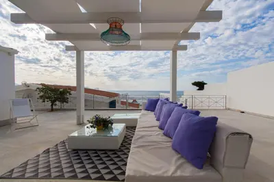 a white couch sitting on a patio with purple pillows at Marina Beach Resort by Le Dhome Sicily in Balestrate