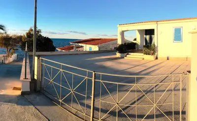 a fence in front of a house next to the ocean at Marina Beach Resort by Le Dhome Sicily in Balestrate