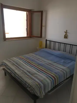 a bedroom with a bed with a striped blanket on it at Casa Del Mulino a Vento in San Vito lo Capo